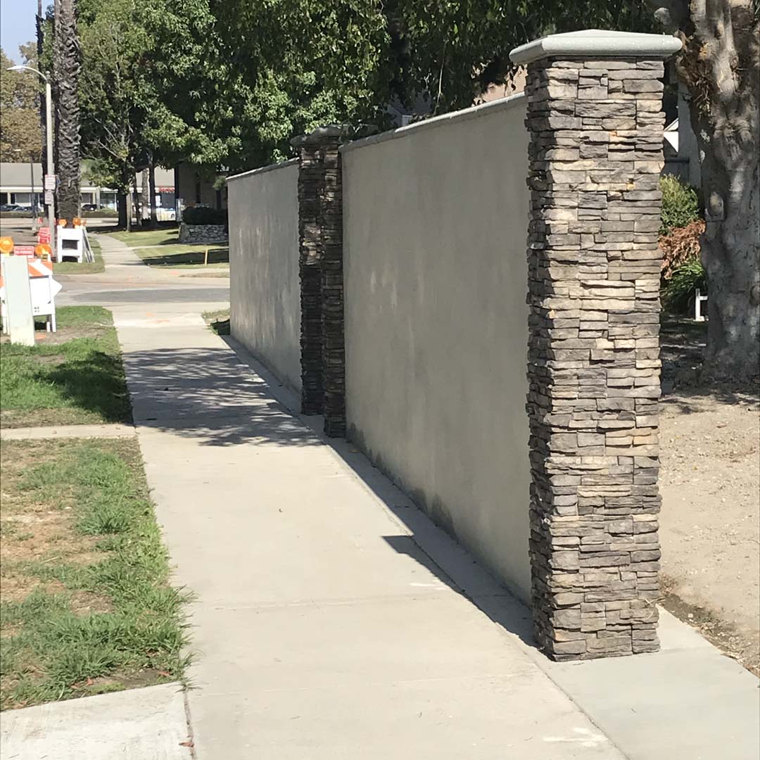 retaining wall made of concrete masonry creating a division between a sidewalk and a backyard